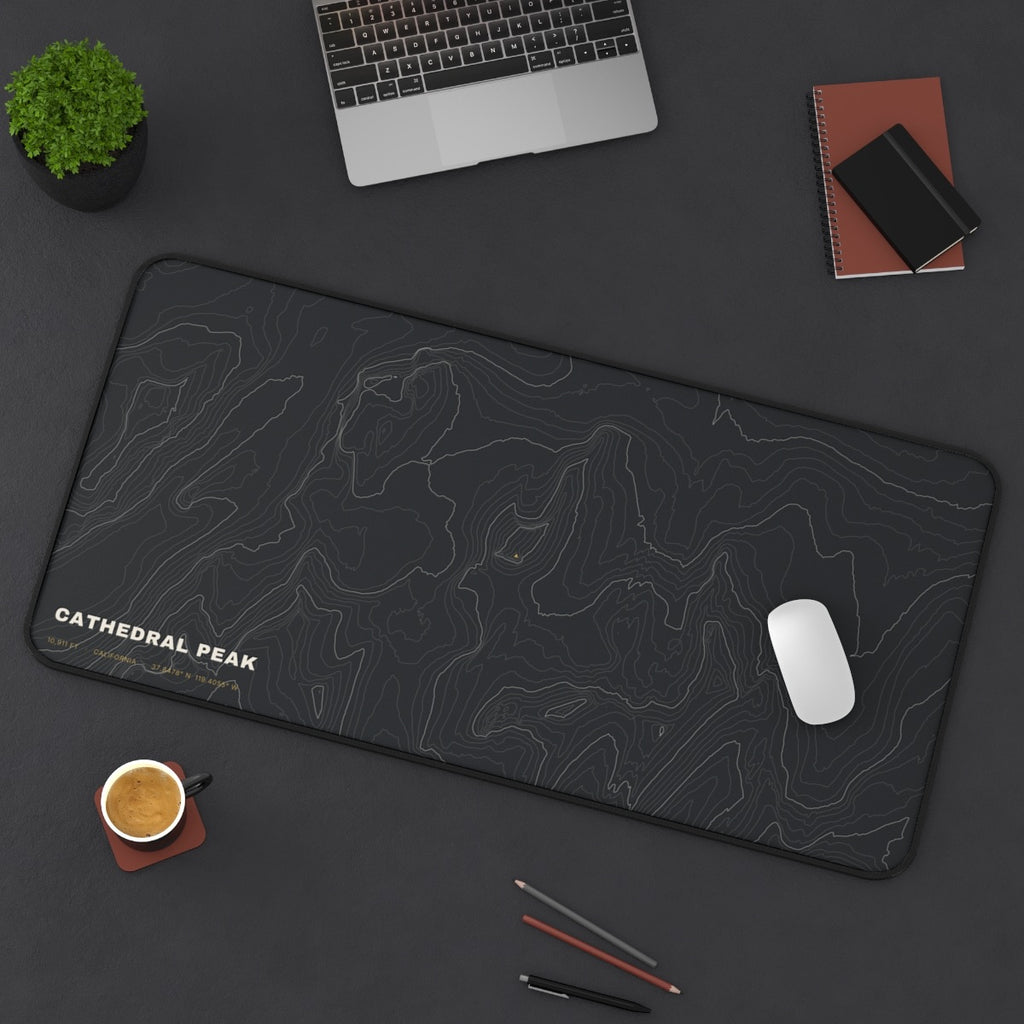 Cathedral Peak Topo desk mat on a desk with a laptop, mouse and coffee cup for scale