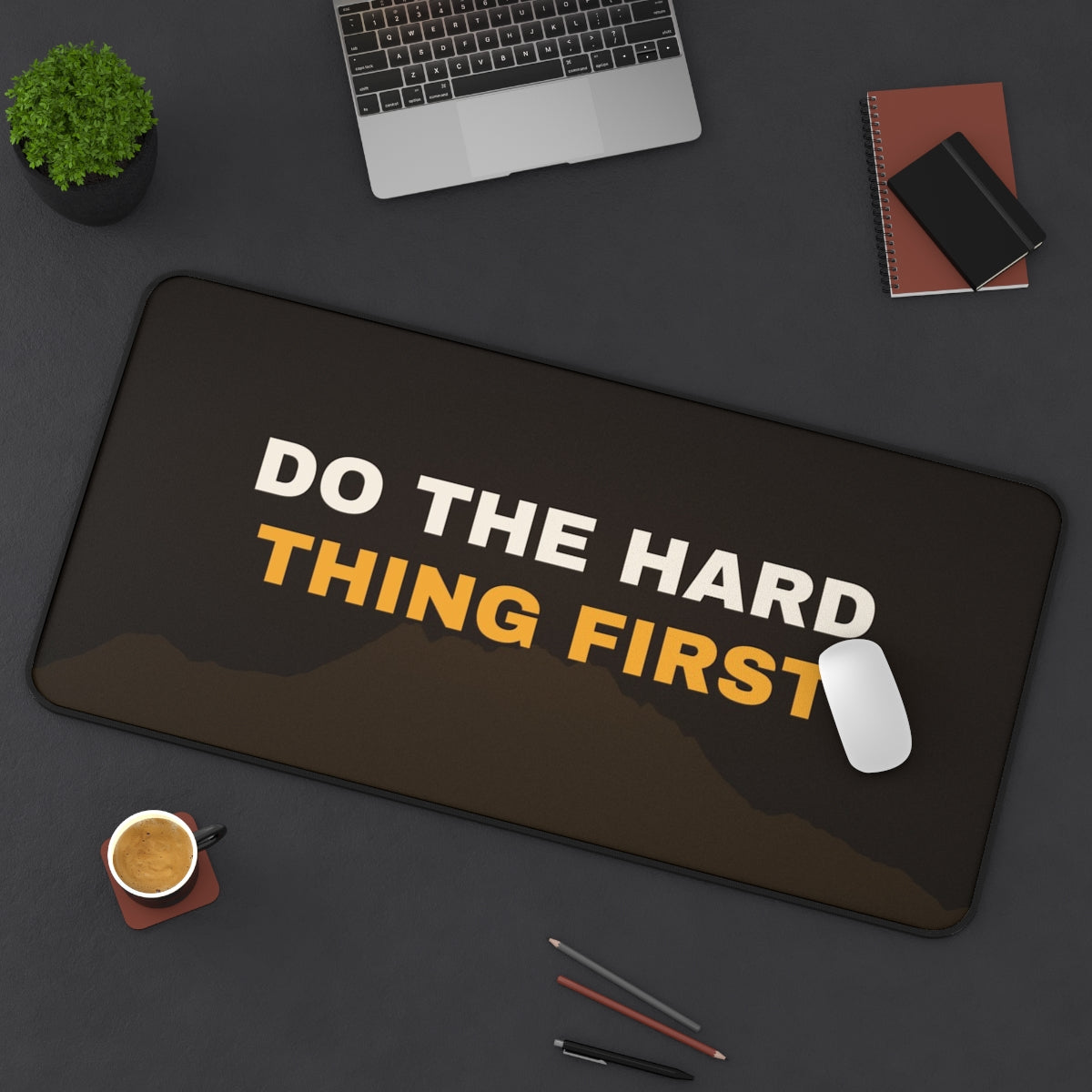 Do the Hard Thing First desk mat on a desk with a laptop, mouse and coffee cup for scale