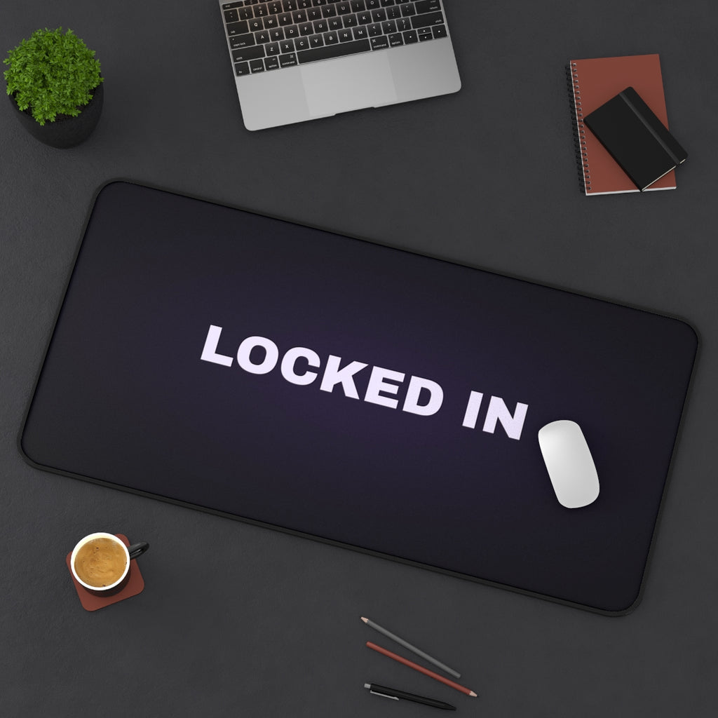 Locked In desk mat on a desk with a laptop, mouse and coffee cup for scale