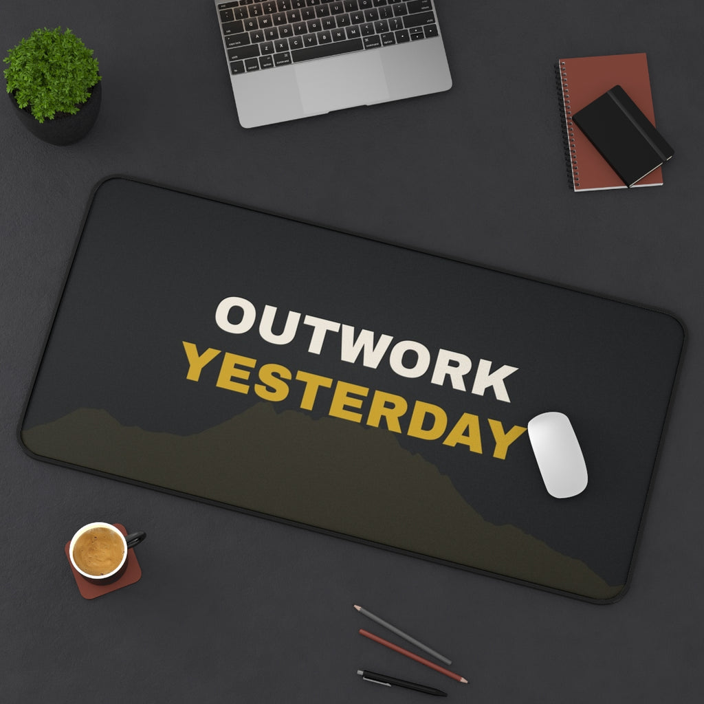 Outwork Yesterday desk mat on a desk with a laptop, mouse and coffee cup for scale