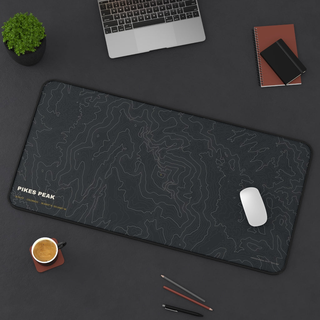 Pikes Peak Topo desk mat on a desk with a laptop, mouse and coffee cup for scale