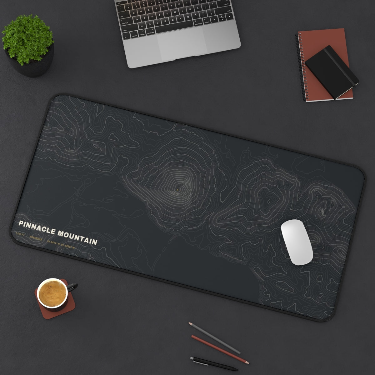 Pinnacle Mountain Topo desk mat on a desk with a laptop, mouse and coffee cup for scale
