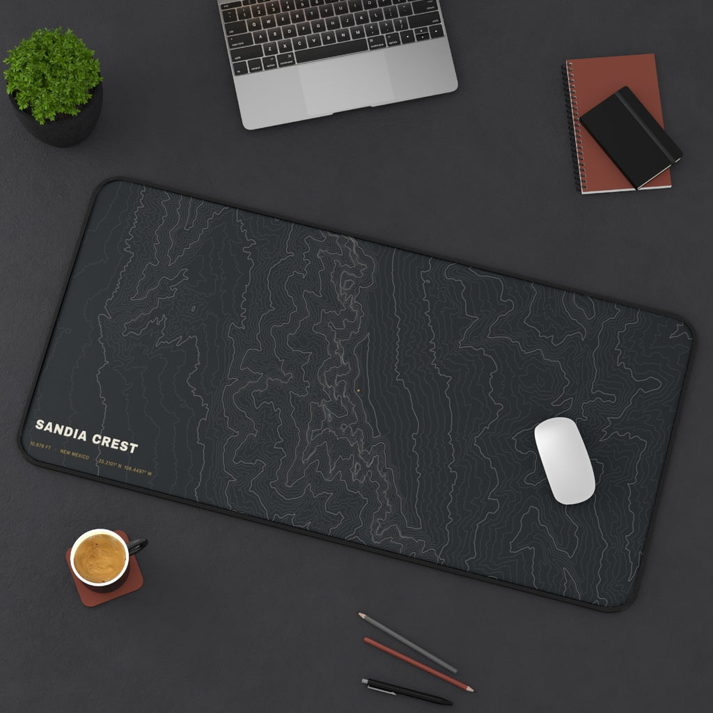Sandia Crest Topo desk mat on a desk with a laptop, mouse and coffee cup for scale
