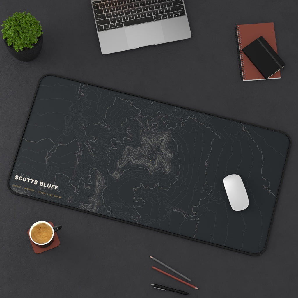 Scotts Bluff Topo desk mat on a desk with a laptop, mouse and coffee cup for scale